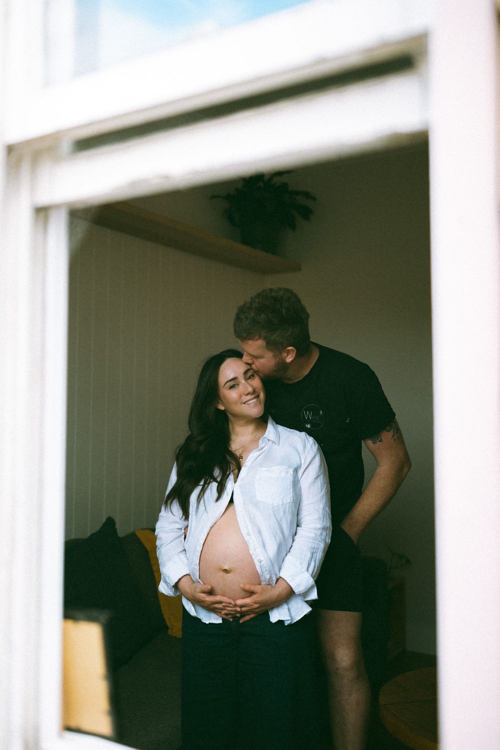 A couple shares an intimate moment together in a series of black and white photos against a white wall.