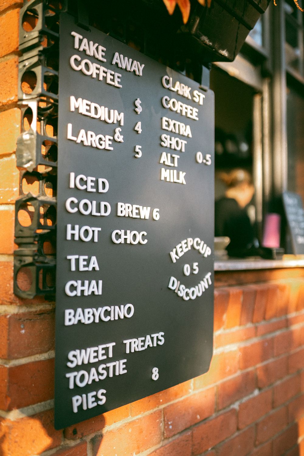 Close-up view of a cafe menu board displaying drink options like coffee, tea, and hot chocolate with prices.