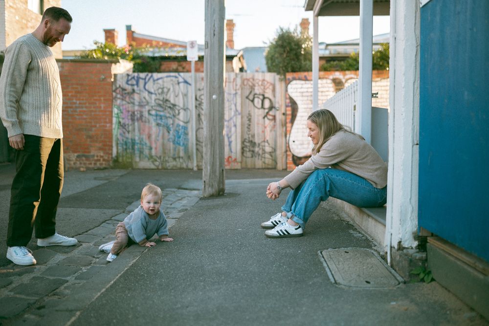 People sit on a concrete ledge against a brick wall in an urban setting at dusk.