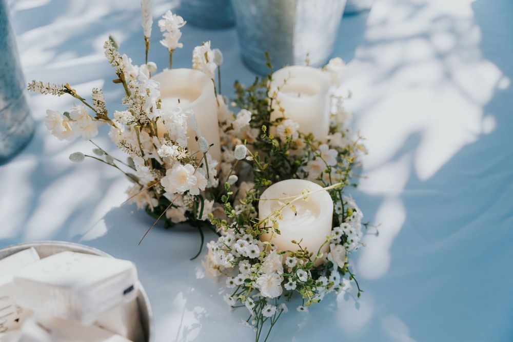 Delicate white roses and baby's breath floral arrangement against light blue fabric background.