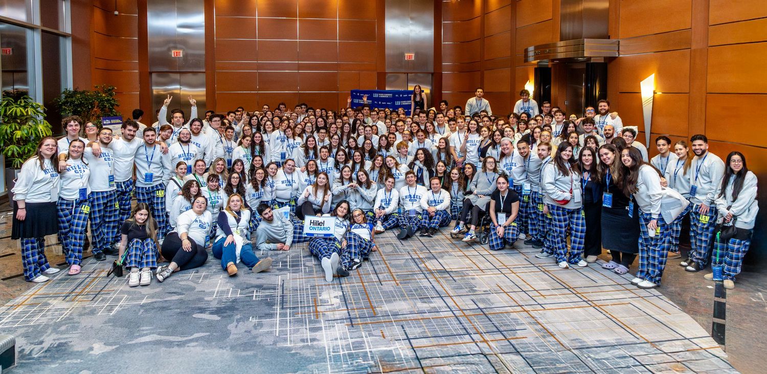 Large group of people in white coats gathered for a panoramic group photo in an auditorium setting.