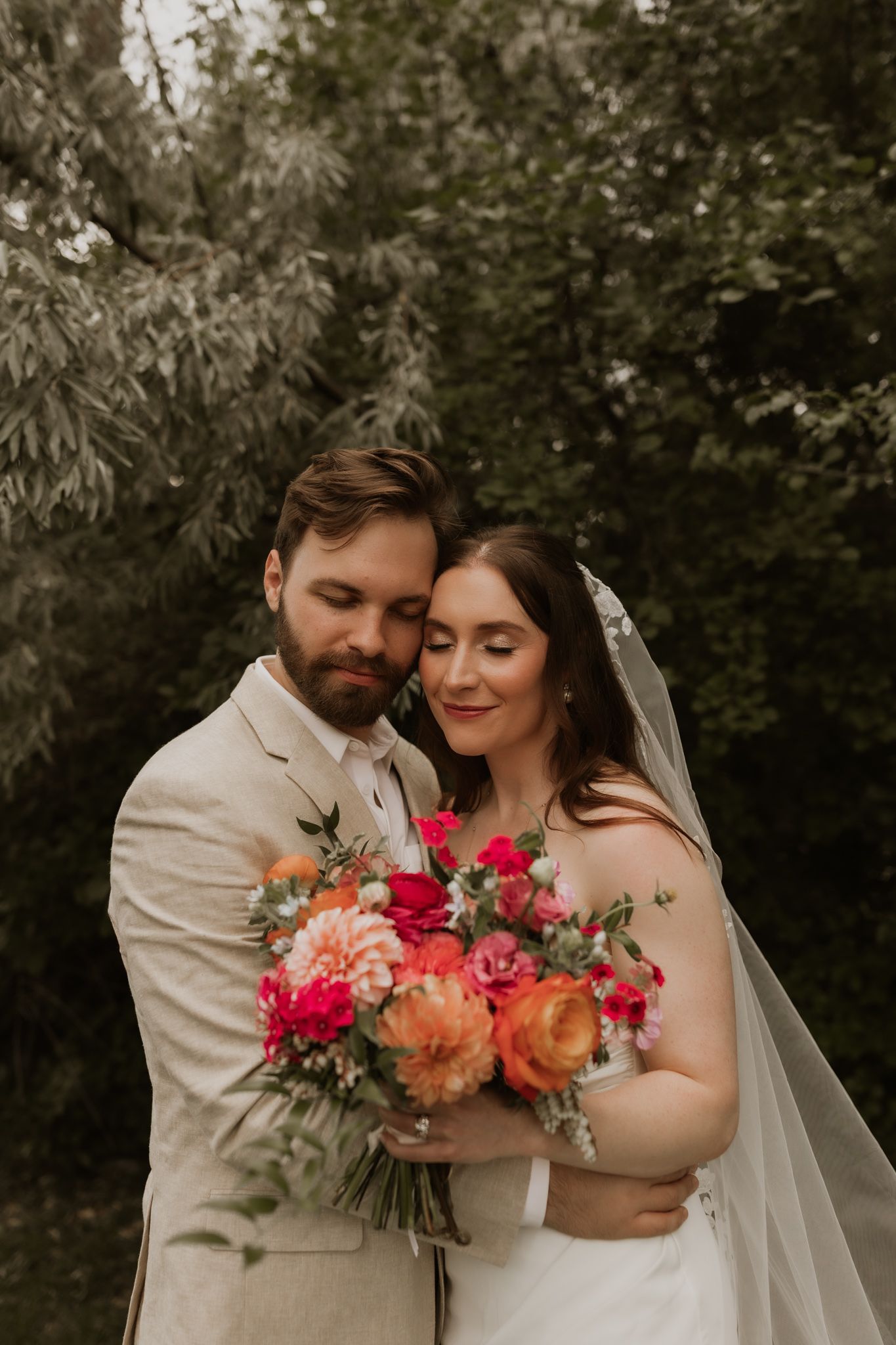 A tender wedding moment captured in a garden setting with bright floral bouquet accents.