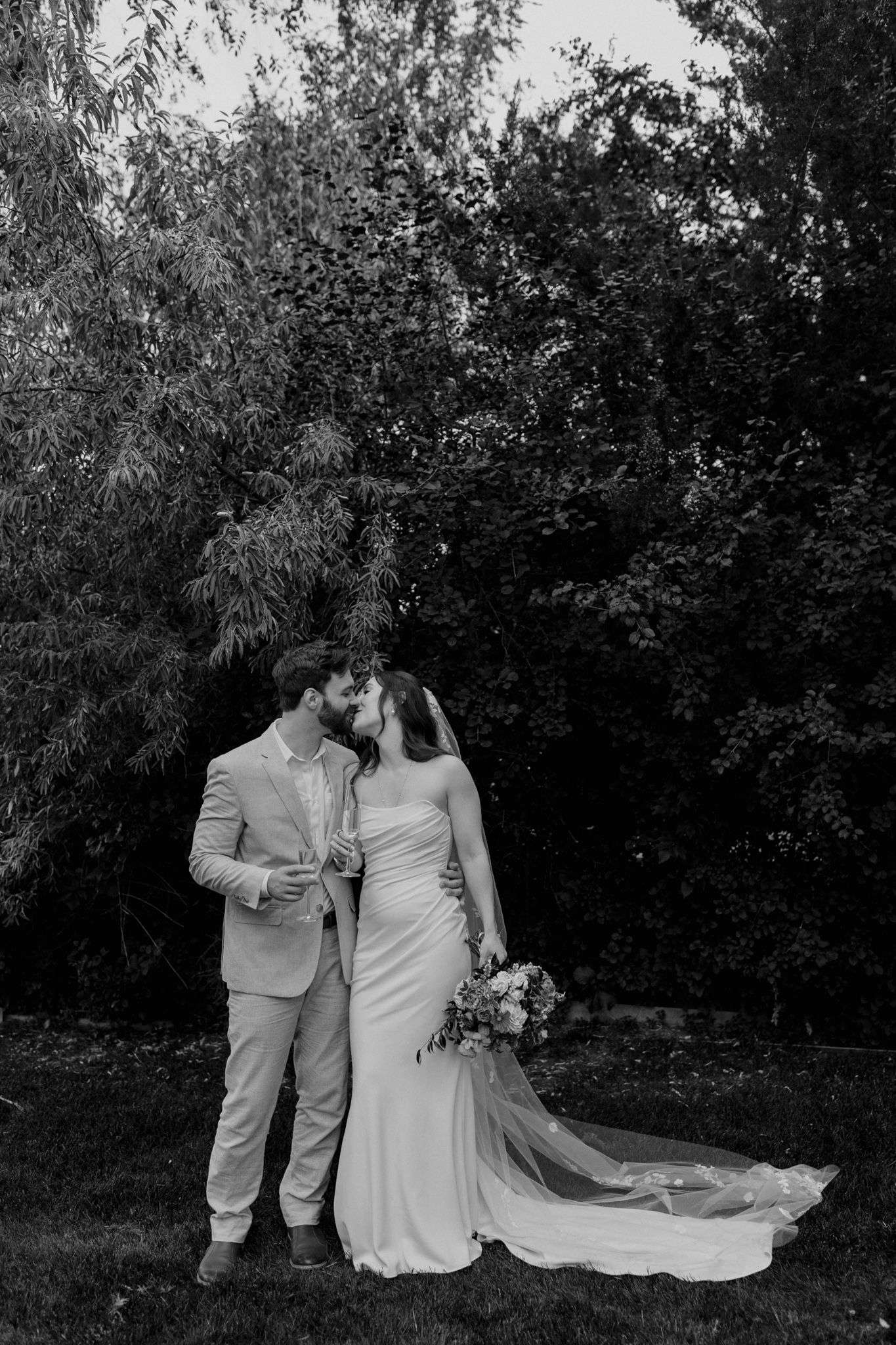 Black and white wedding portrait of a couple in an outdoor garden setting.