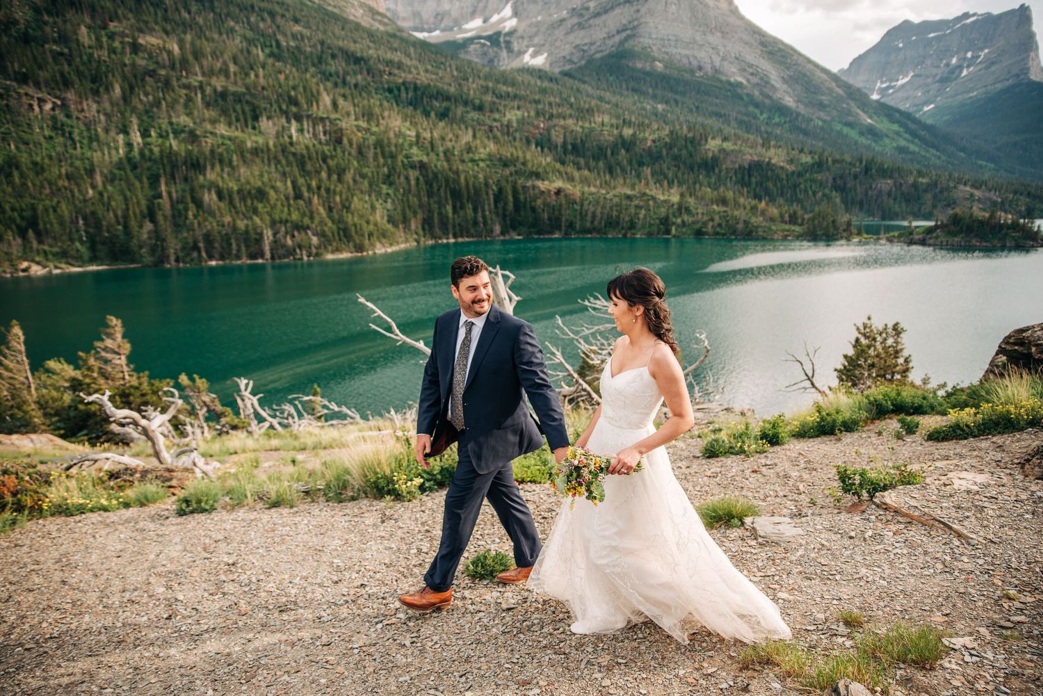 Wedding couple celebrates with scenic mountain lake and forest backdrop in Canadian Rockies.