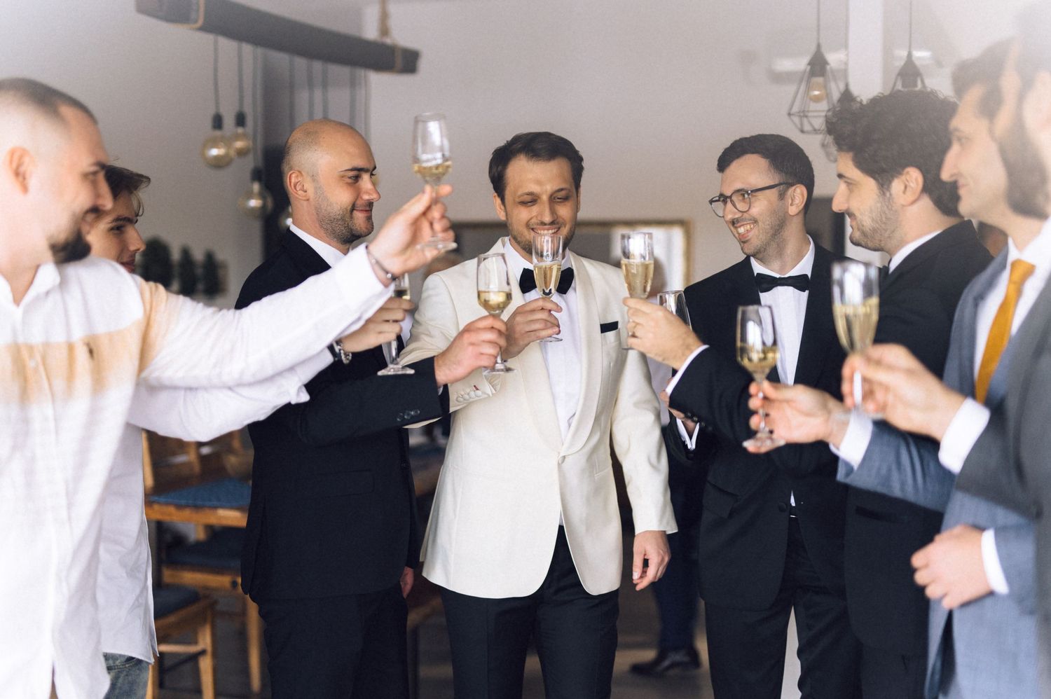 A group of well-dressed guests raise champagne glasses in a toast at an elegant celebration.