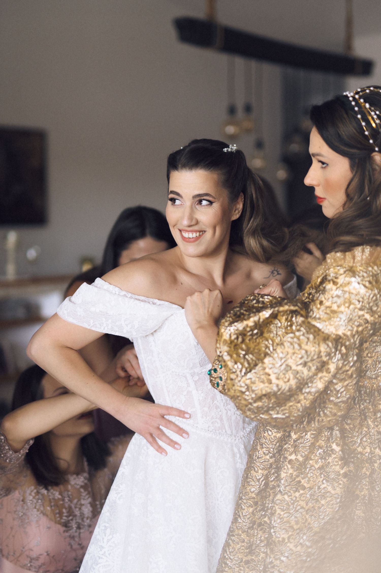 Two people embrace in an emotional moment, one wearing a white wedding dress and the other in a sparkling gold gown.