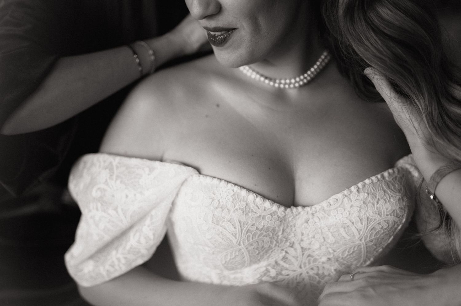 Close-up details of a white lace wedding dress bodice with delicate beading and pearl embellishments.
