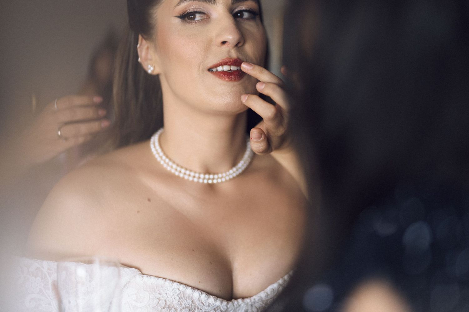 Elegant woman in white corset dress wearing pearl choker necklace in soft focus portrait.