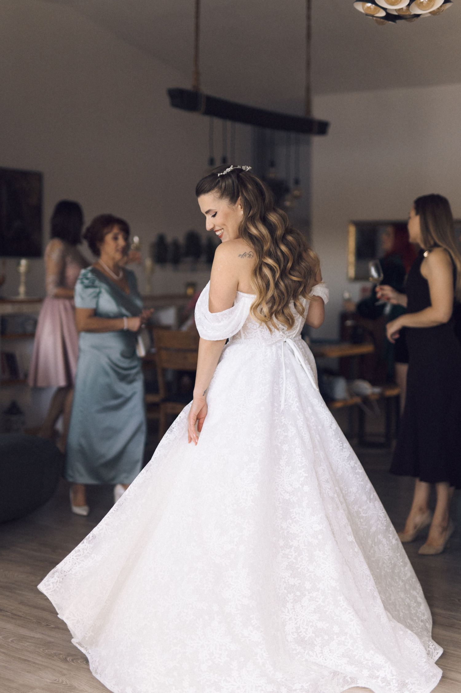 A flowing white wedding dress with lace details twirls gracefully on a dance floor during a celebration.