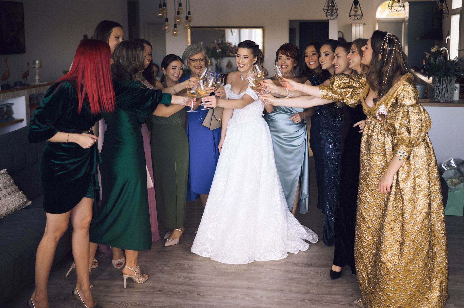 Wedding party forms a dance line at a reception with guests wearing elegant dresses in various colors.