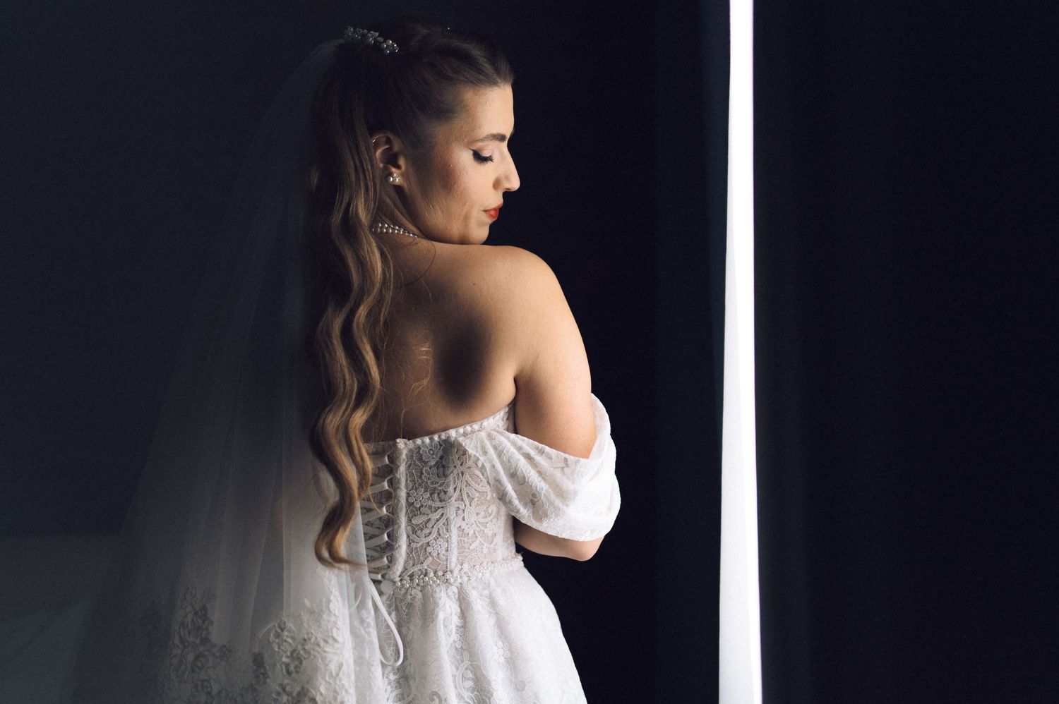 A series of romantic bridal portraits showing details of a white lace wedding dress against a dark background.