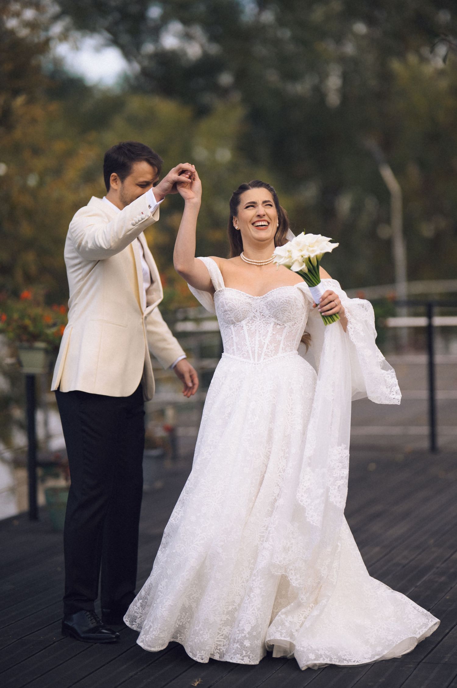 A couple in wedding attire dances together in a sequence of romantic twirling movements on a dark surface outdoors.