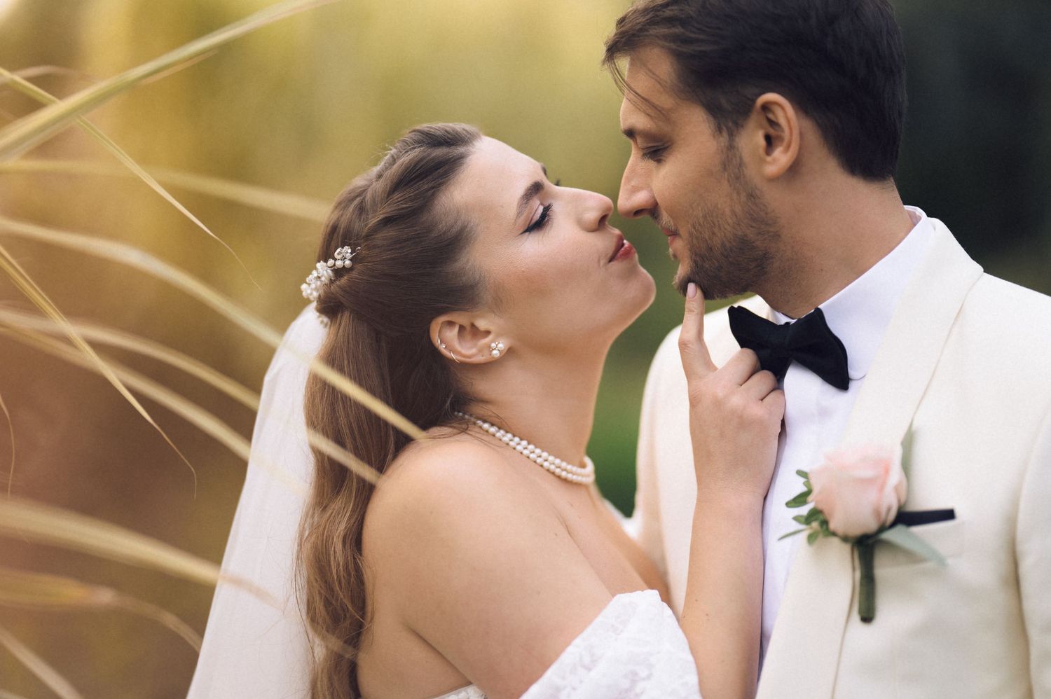 A romantic couple shares a tender kiss during their wedding ceremony with a soft golden bokeh background.