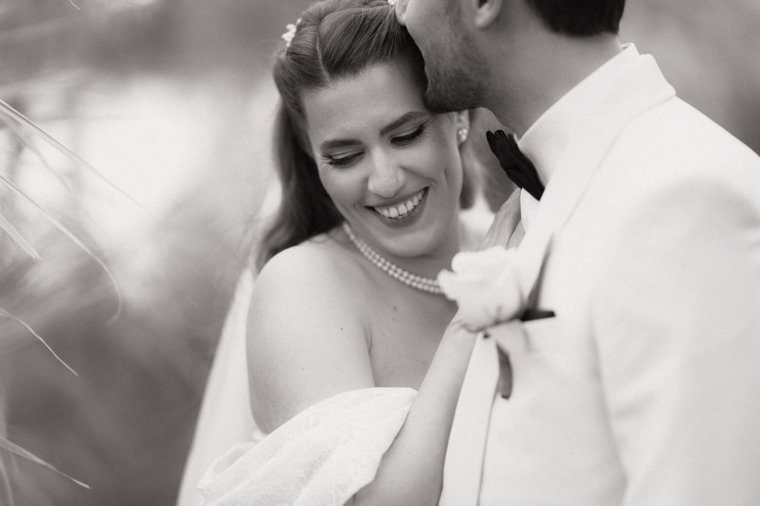 A joyful black and white wedding photo showing a romantic moment between newlyweds in an intimate embrace.
