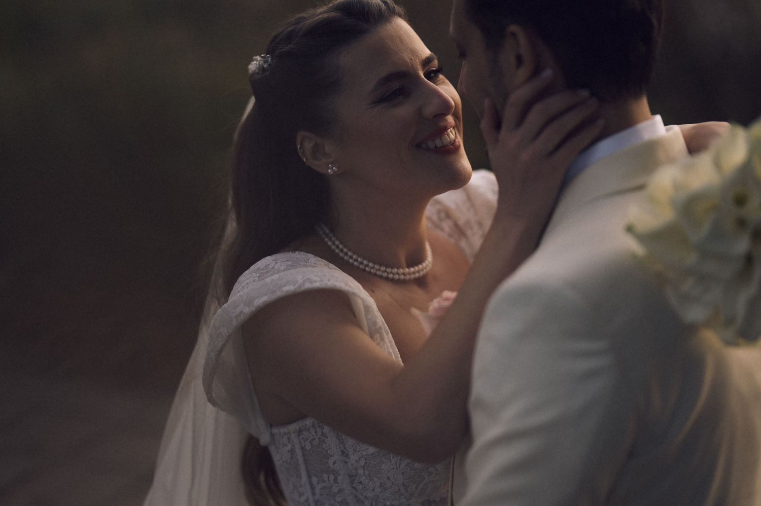 A romantic wedding couple shares a passionate kiss during their outdoor ceremony in soft natural lighting.
