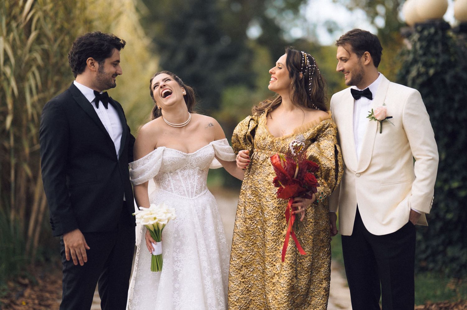 A wedding party poses together outdoors in formal attire with bridesmaids wearing gold sequined dresses.
