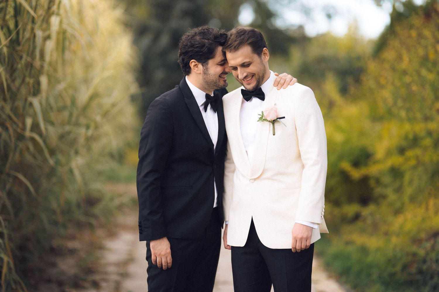 A romantic couple in formal wedding attire share an intimate moment together in a lush outdoor garden setting.