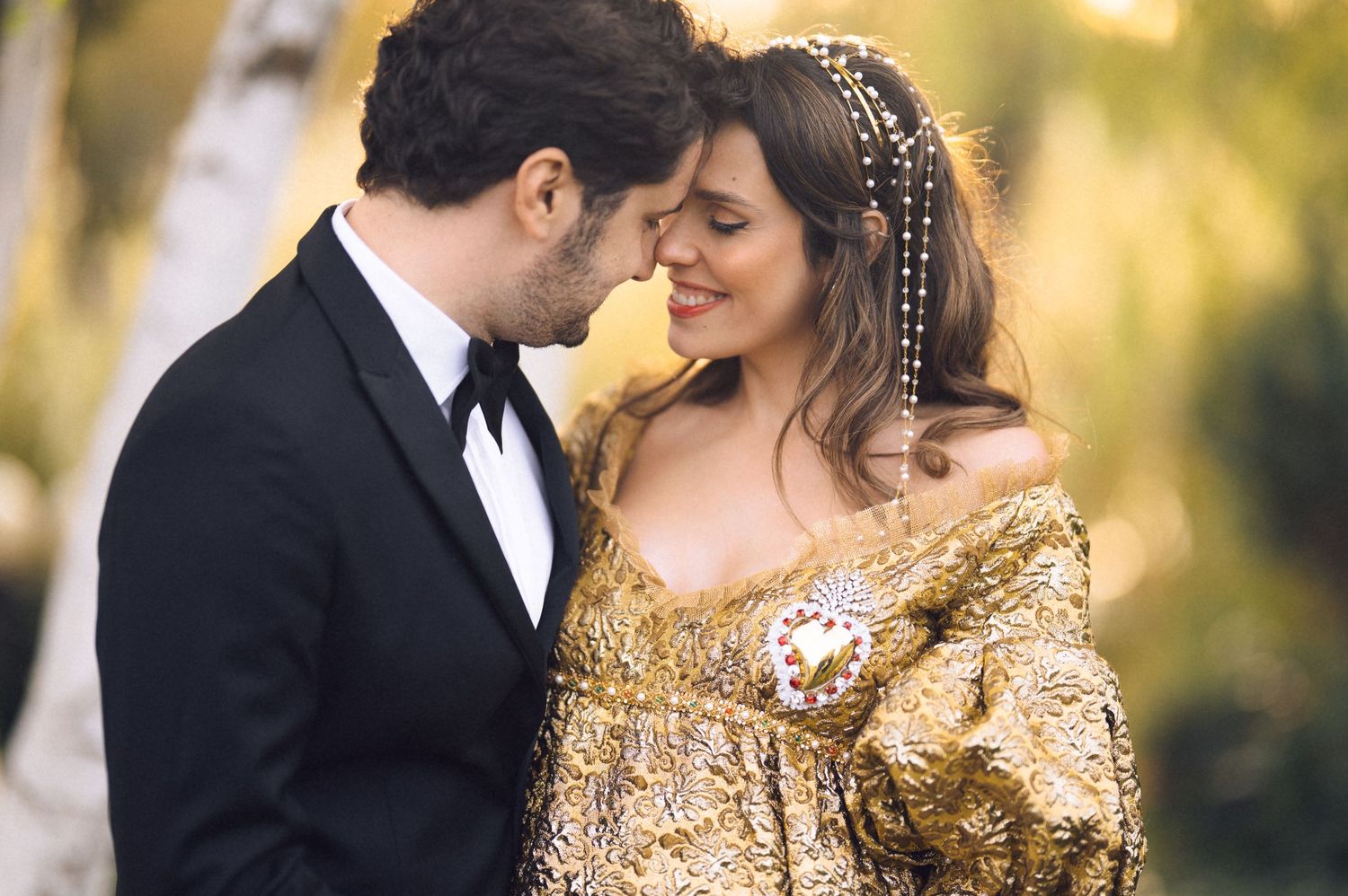 A romantic couple in formal attire share intimate moments in a golden-lit outdoor setting during a photo session.