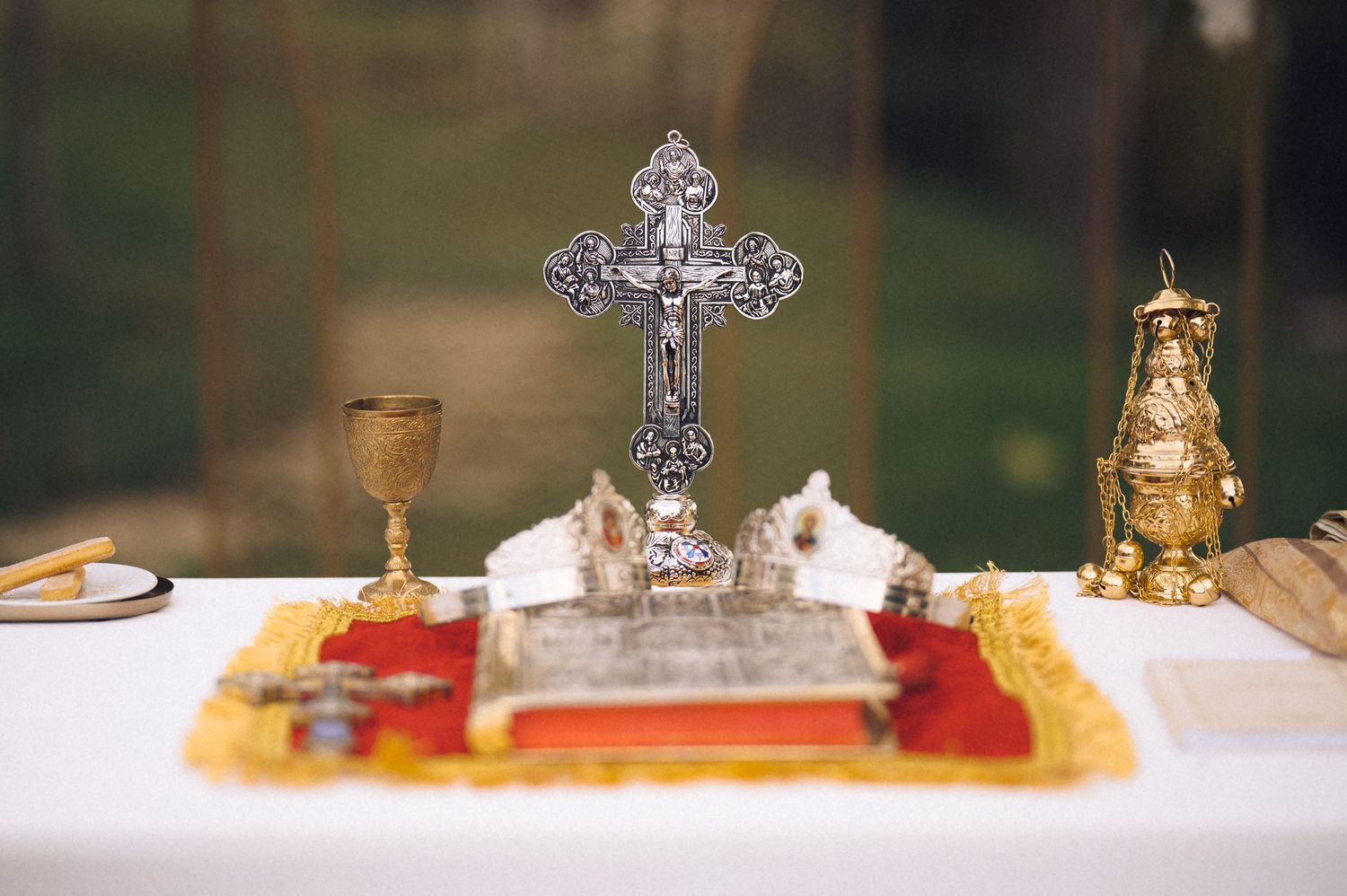 Religious artifacts including ornate crosses and ceremonial objects displayed on a white surface with blurred background.