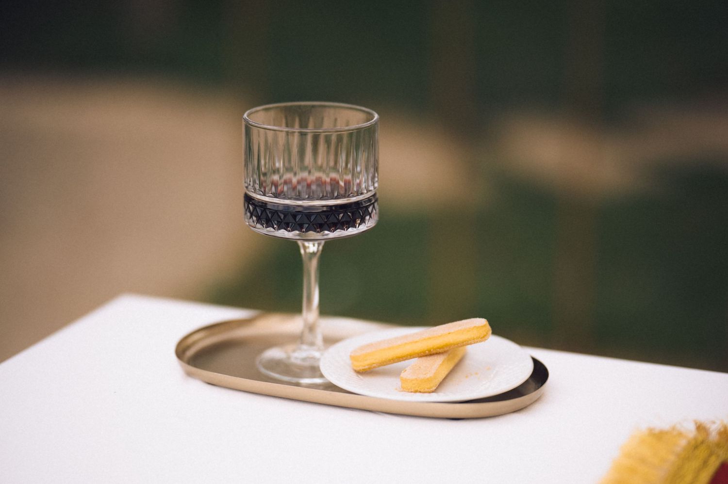 A rustic wooden table setting with wine glasses, plates, and decorative elements in warm natural lighting.