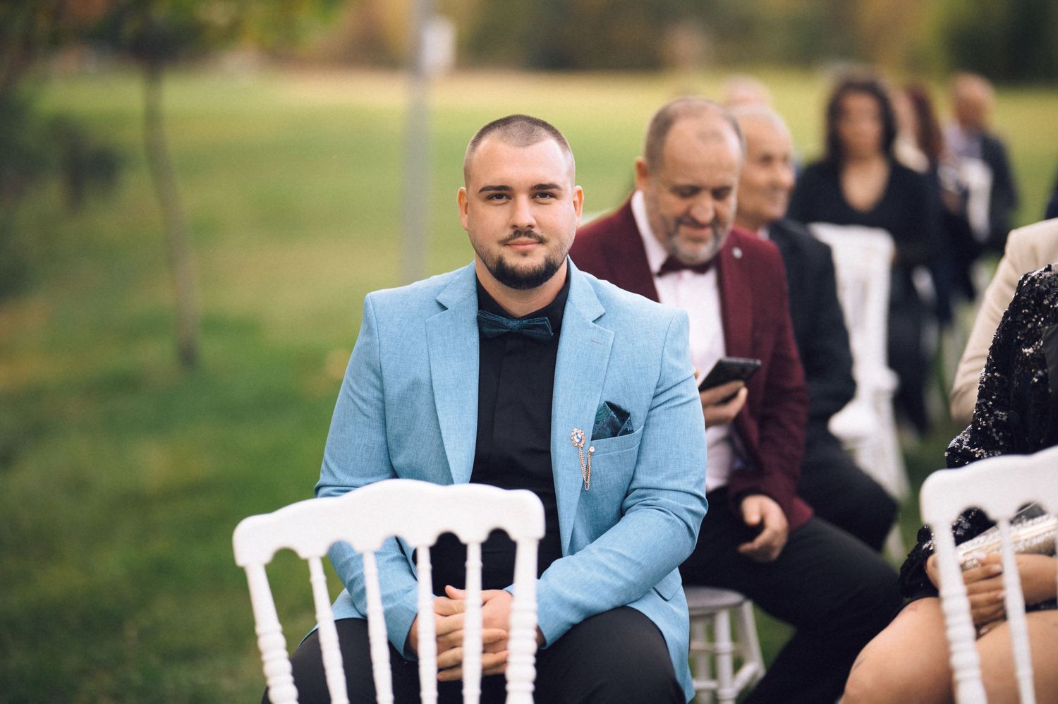 A group of wedding guests enjoying an outdoor reception on a sunny day.