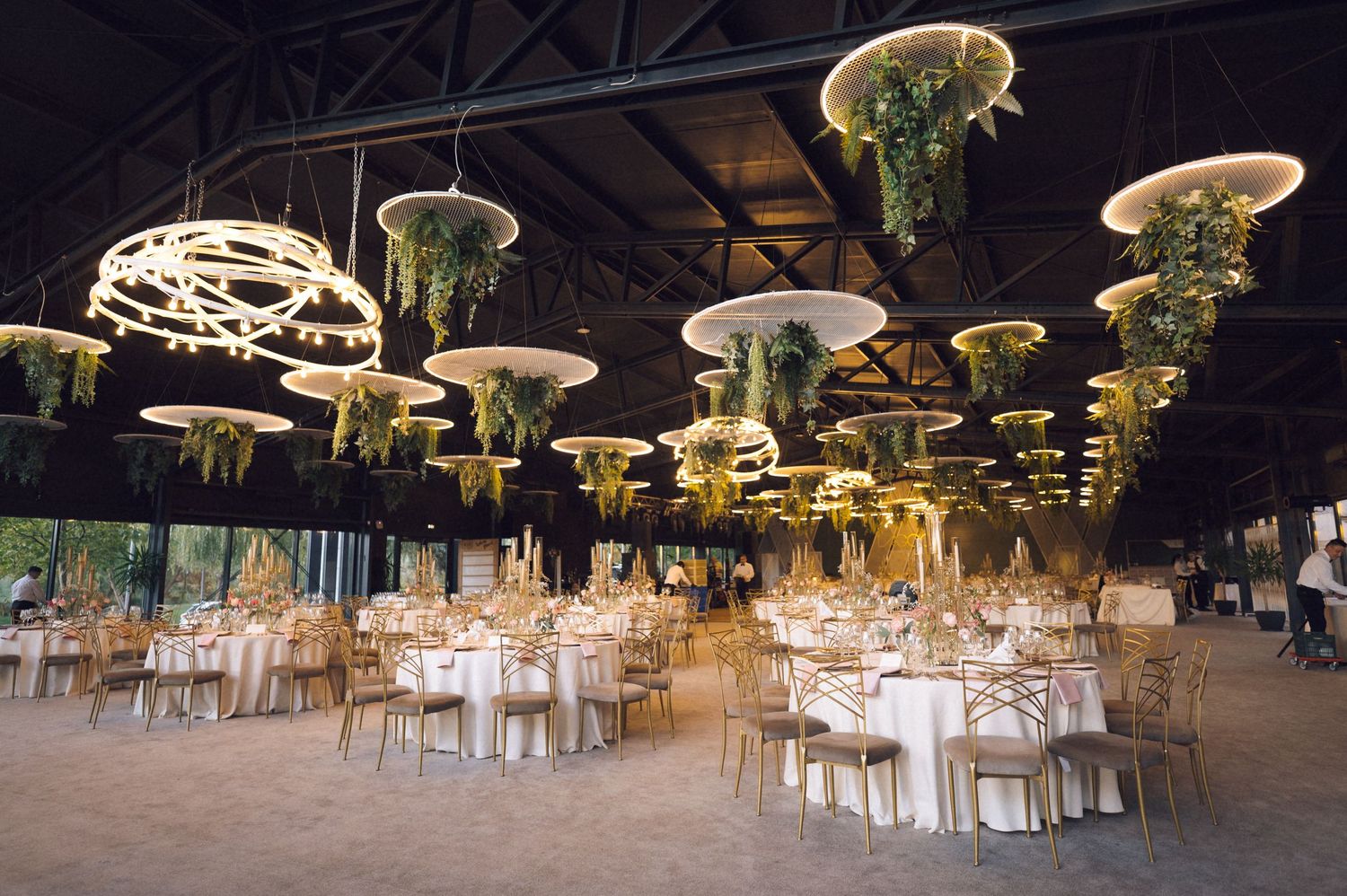 Elegant outdoor wedding reception setup with illuminated mushroom-shaped lights hanging over white dining tables and chairs.
