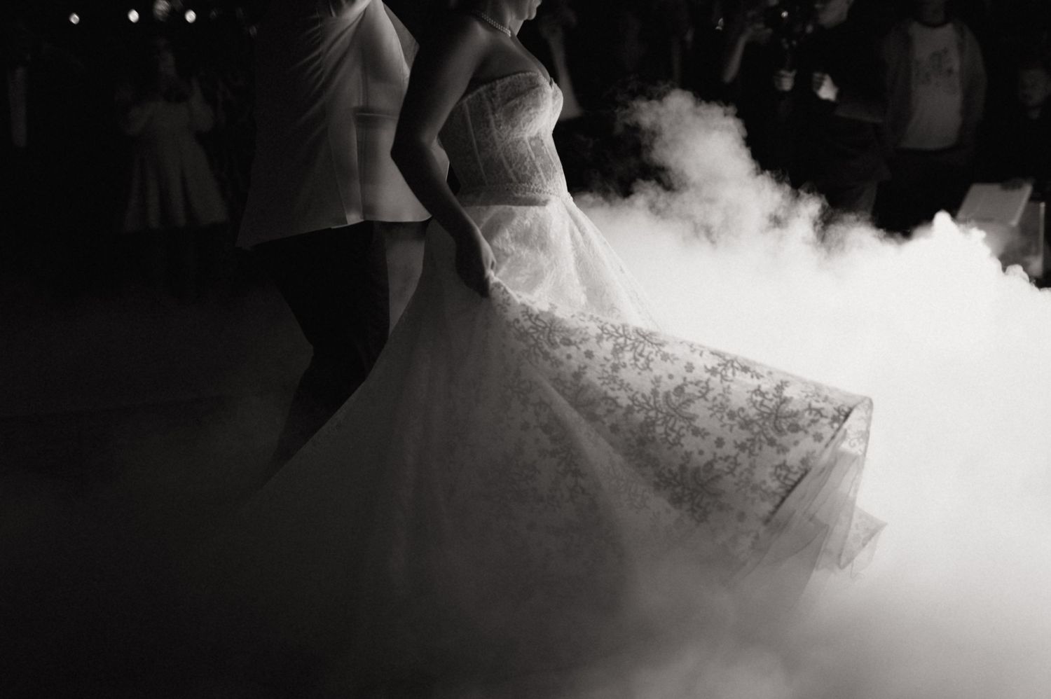 Wedding dresses are showcased in dramatic black and white with ethereal fog swirling around the flowing gowns.