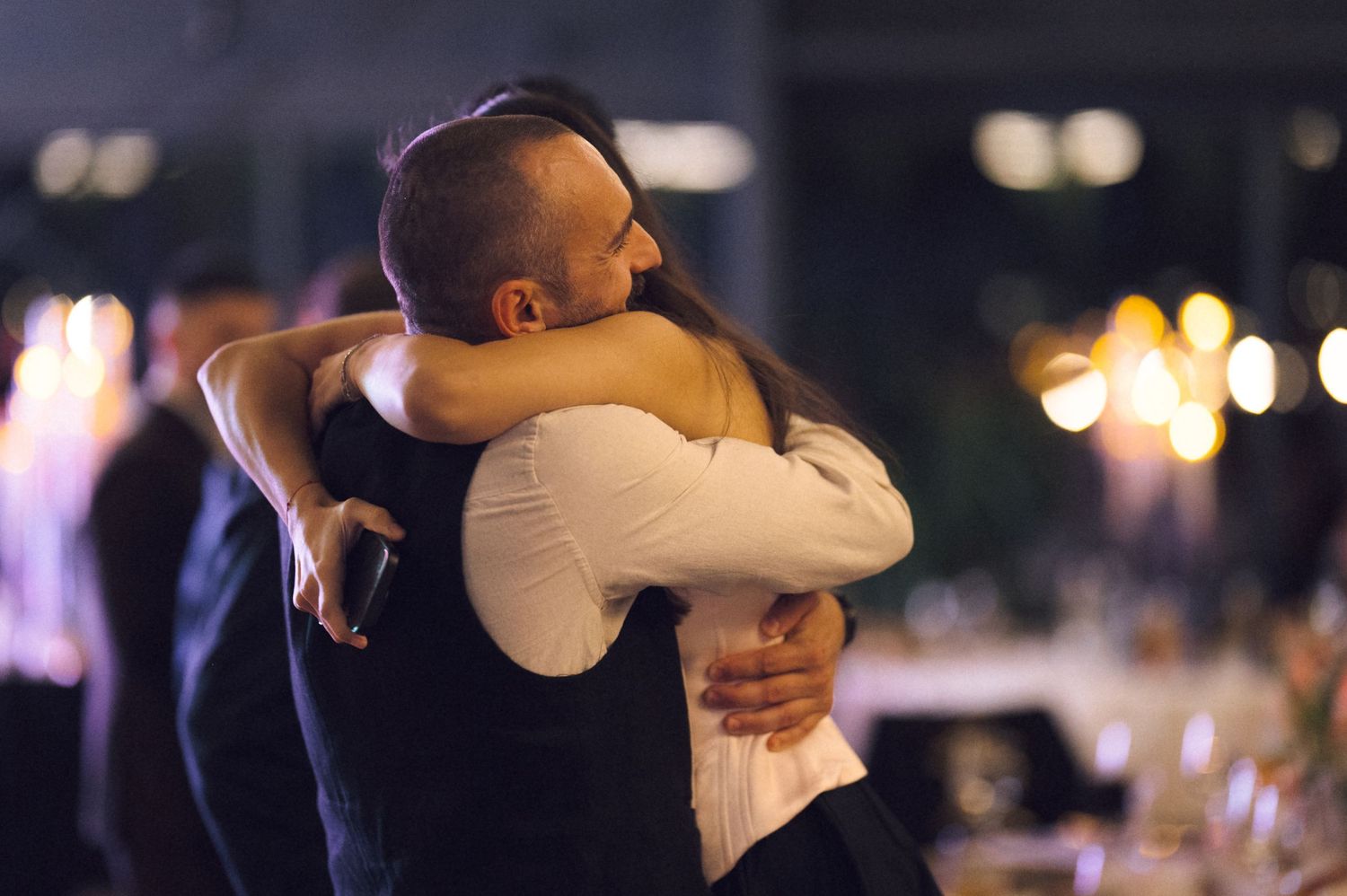 Couples dancing together at an evening social event with soft lighting and bokeh effects in the background.