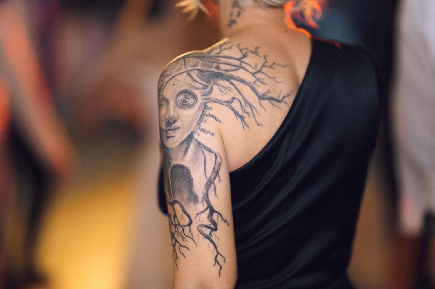Close-up view of detailed black and gray tree branch tattoo artwork on person's arm.