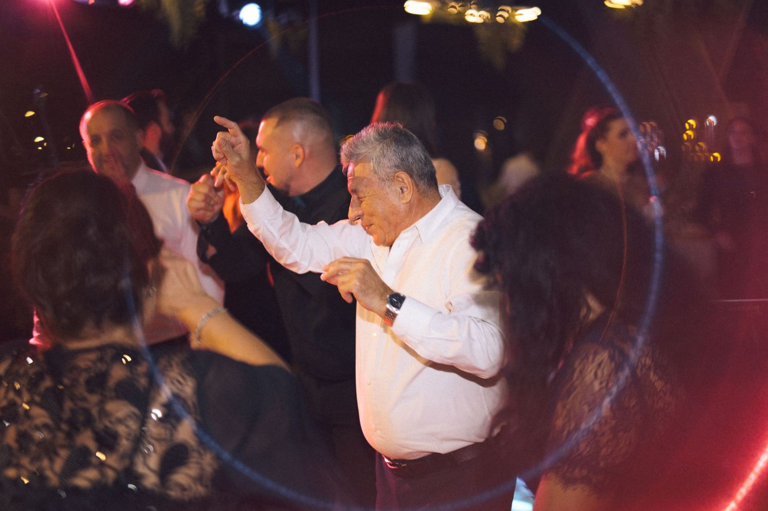 Dance floor scene at a nighttime event with red lighting and silhouettes of people dancing.