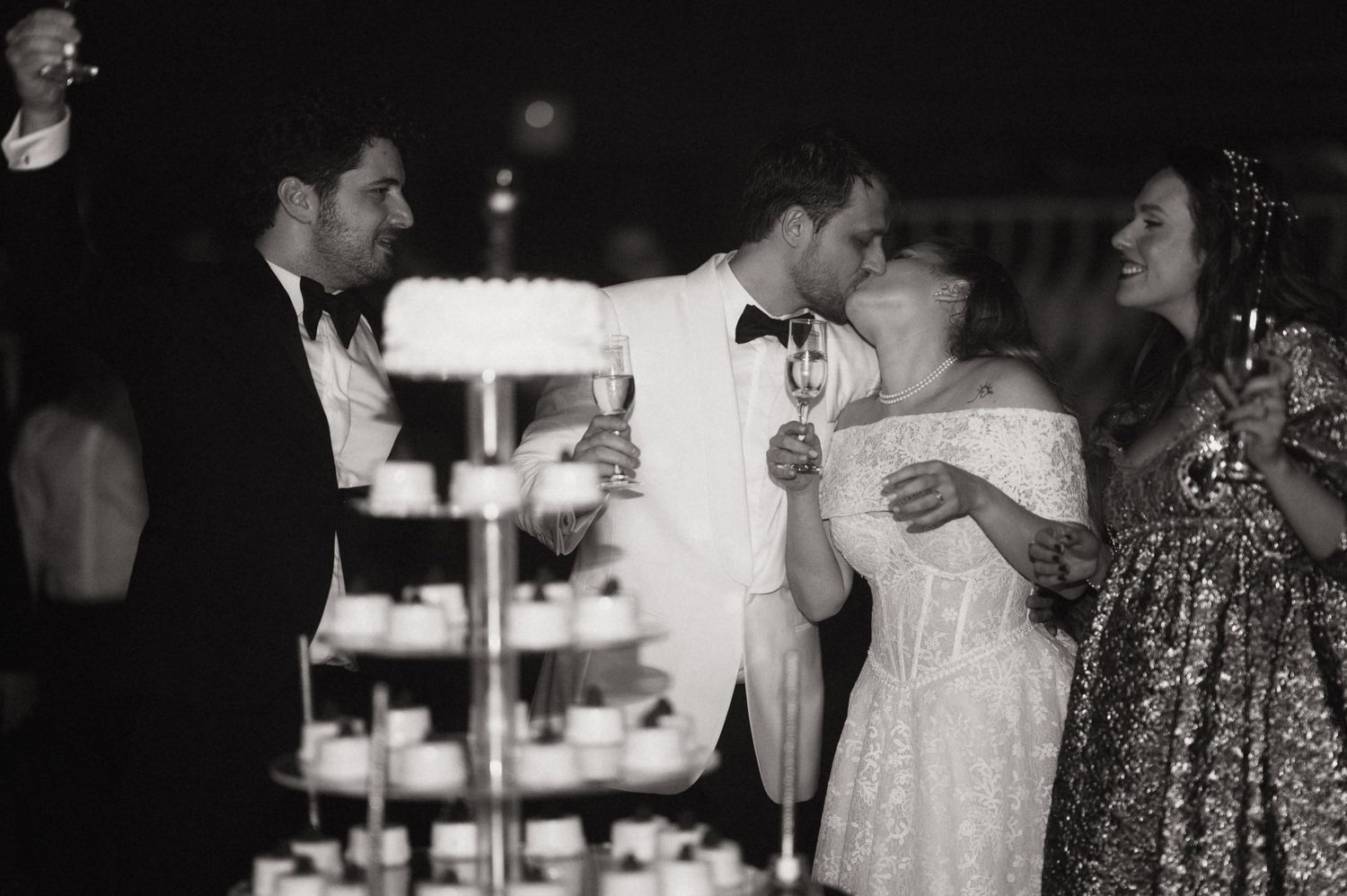 A group of people dancing and socializing at a dimly lit party or reception.