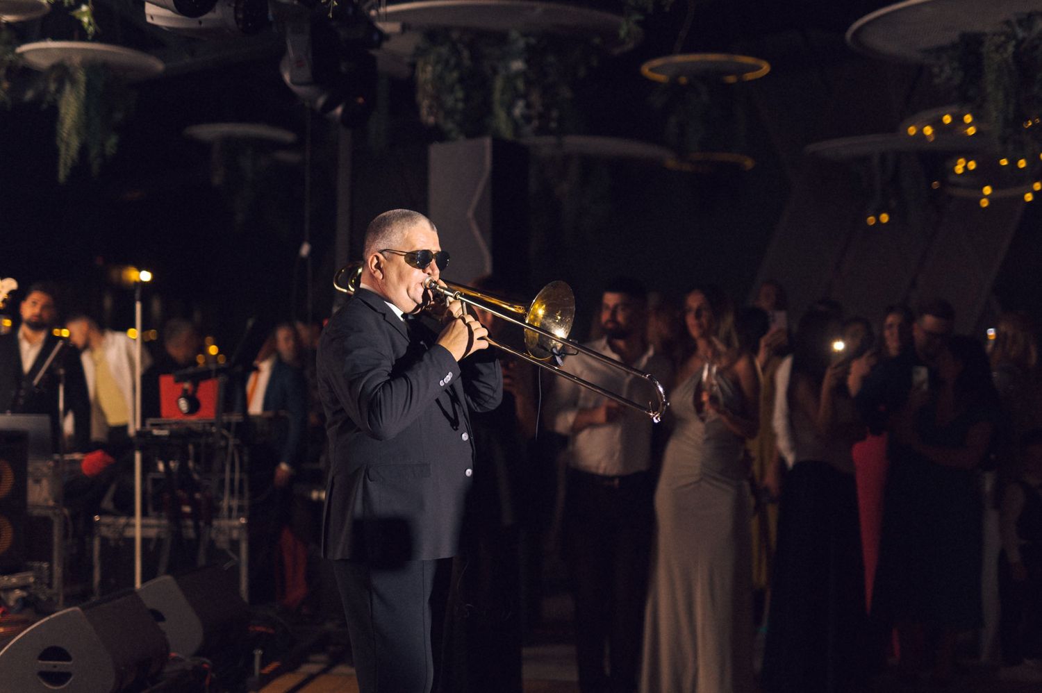 People gathered in a dark room illuminated by soft lighting at what appears to be an evening event.