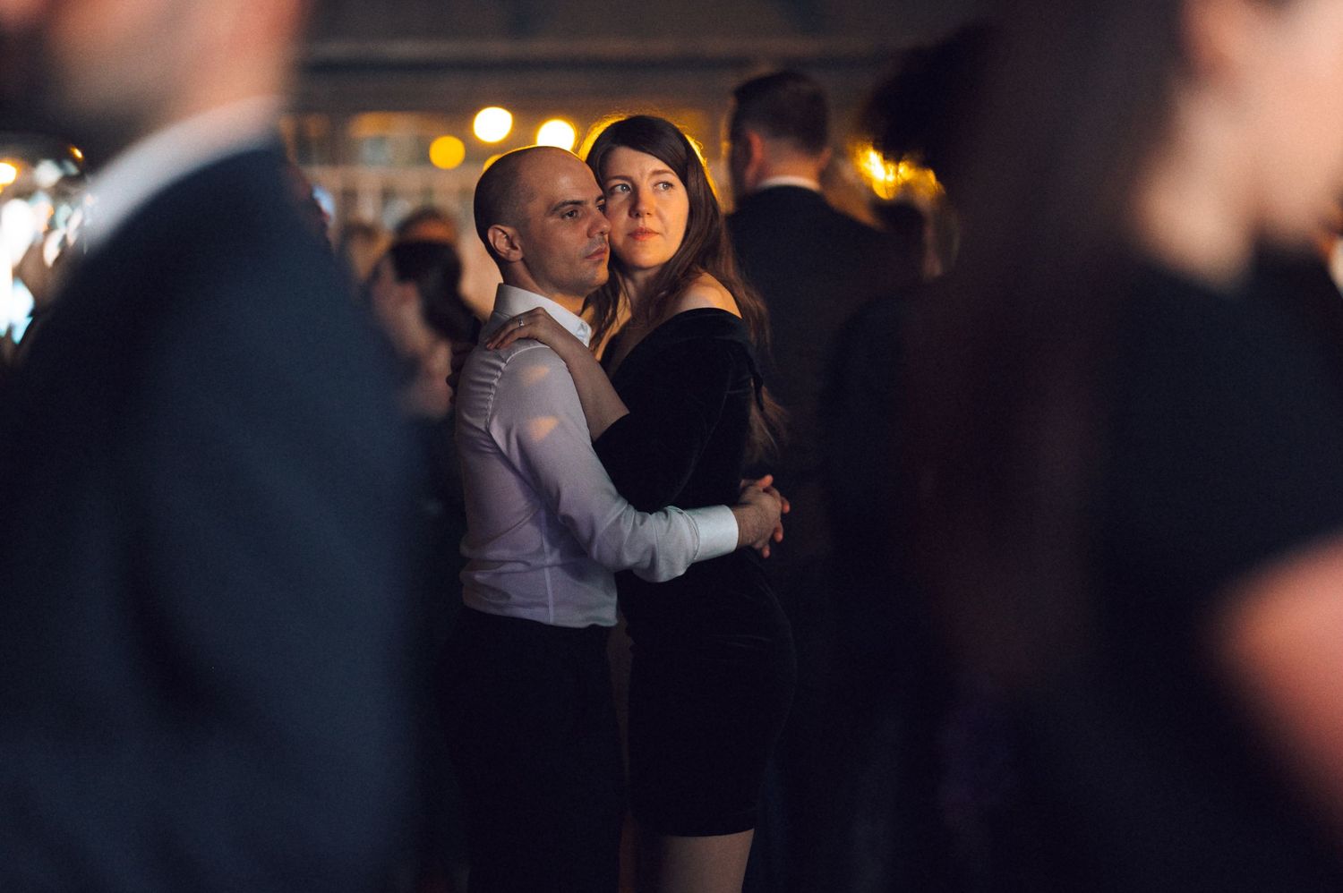 Blurry nighttime crowd scene with dark silhouettes of people dancing and socializing at what appears to be a party or club.