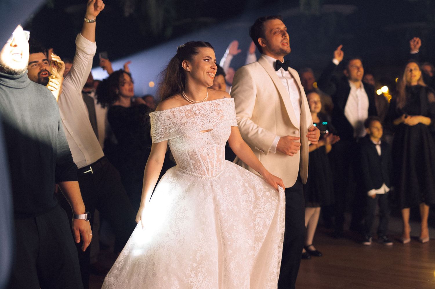 A couple dances together during their first dance at a wedding reception with guests watching in the background.
