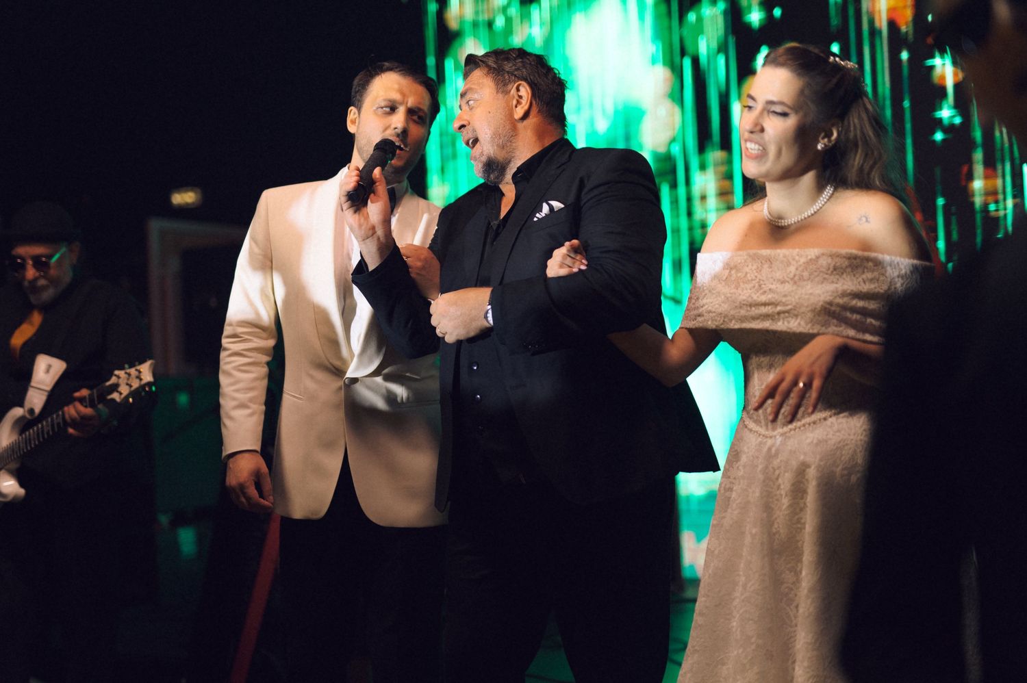 Couples dancing together at a wedding reception with green lighting and decorative elements in the background.