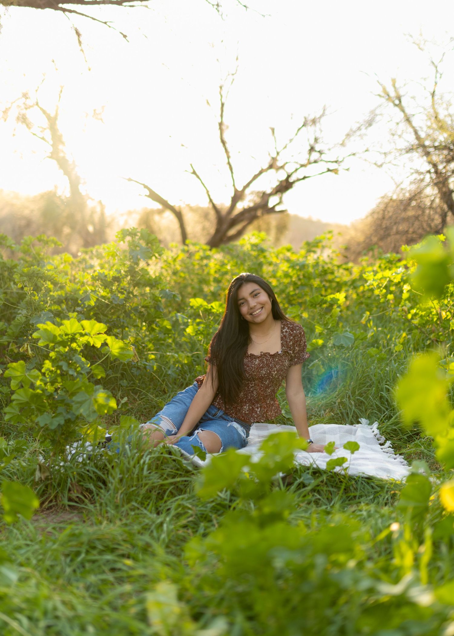 A white picnic blanket spread out in a field of vibrant yellow wildflowers during golden hour sunset.