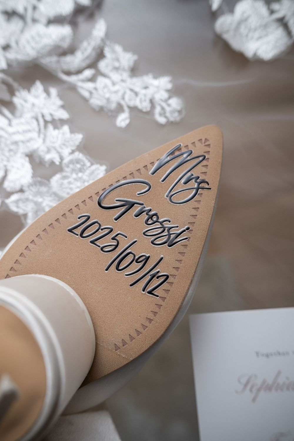 Handwritten table numbers on brown kraft paper napkin rings displayed with white lace decor for elegant wedding reception.