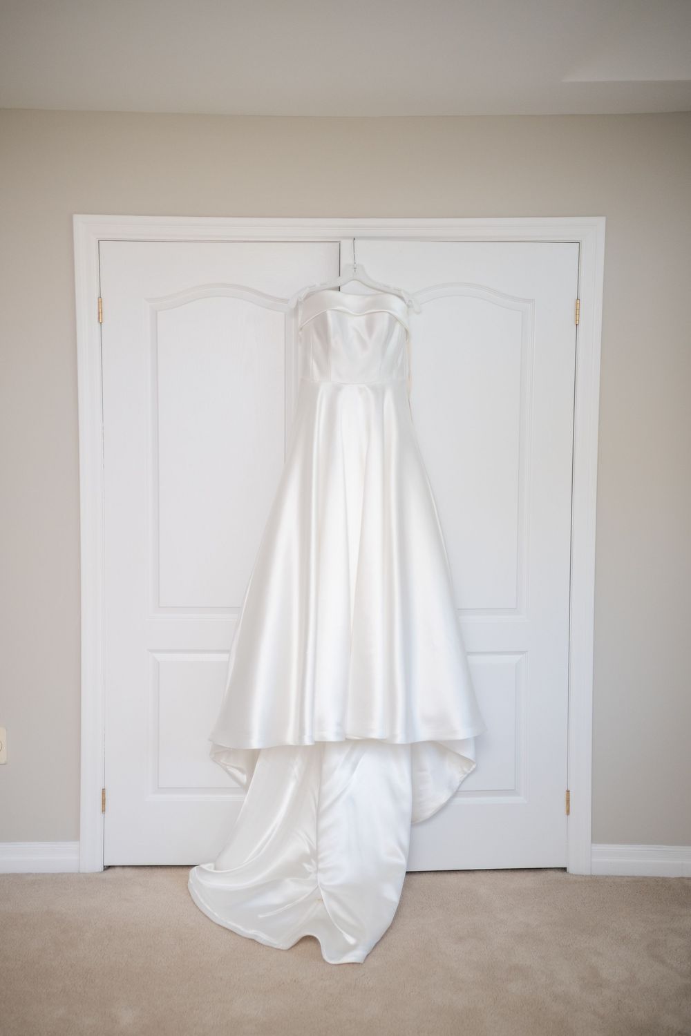 A white ghost-like sheet hangs mysteriously in front of a white door and beige carpet, creating an eerie Halloween scene.