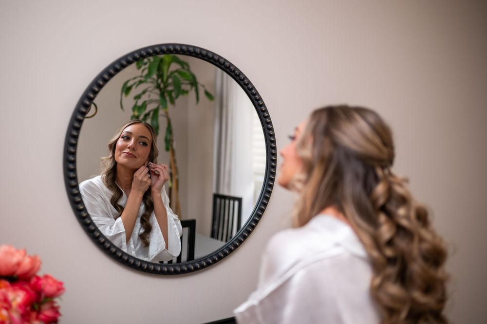 A collection of circular mirrors on a wall reflects someone preparing for a special occasion in a white top.
