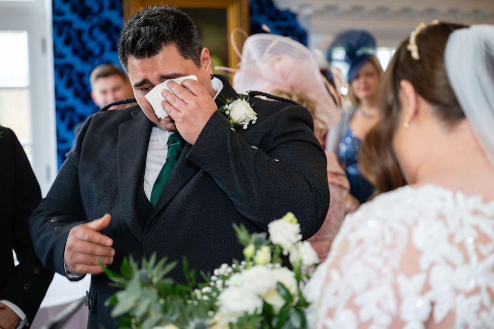 Wedding ceremony participants sharing emotional reactions in formal attire.