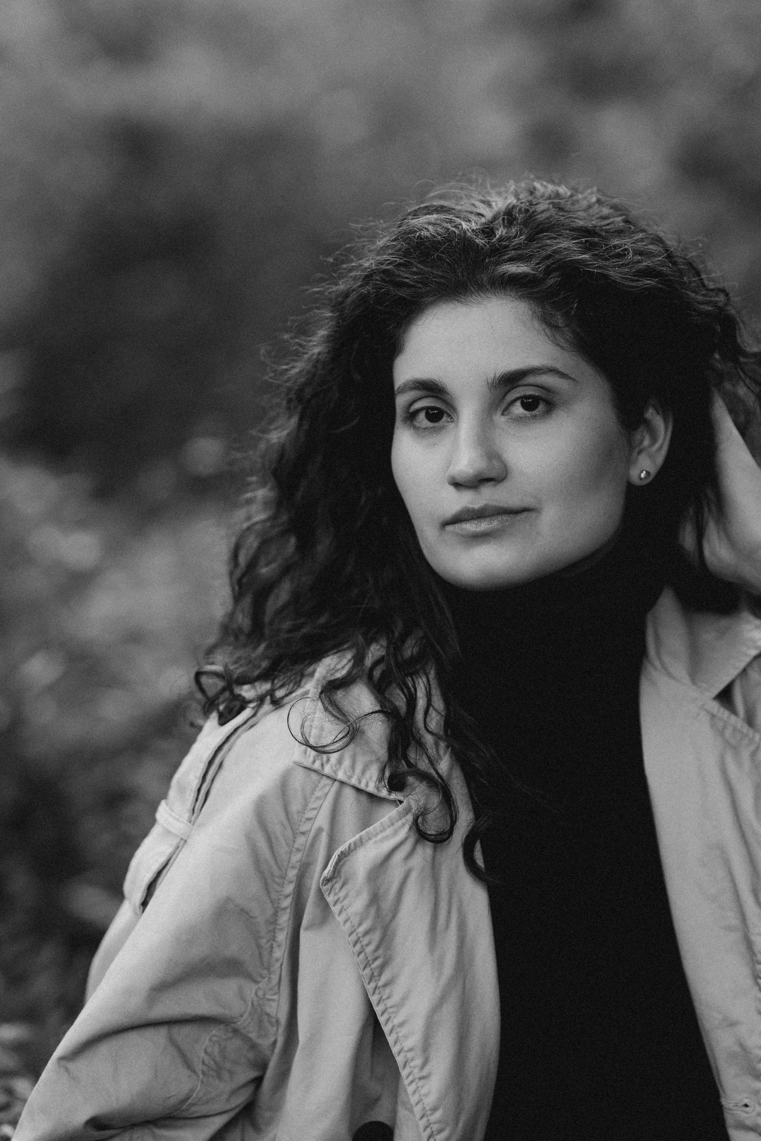 Black and white artistic portrait sequence showing a person with curly hair in a light colored coat looking to the side.