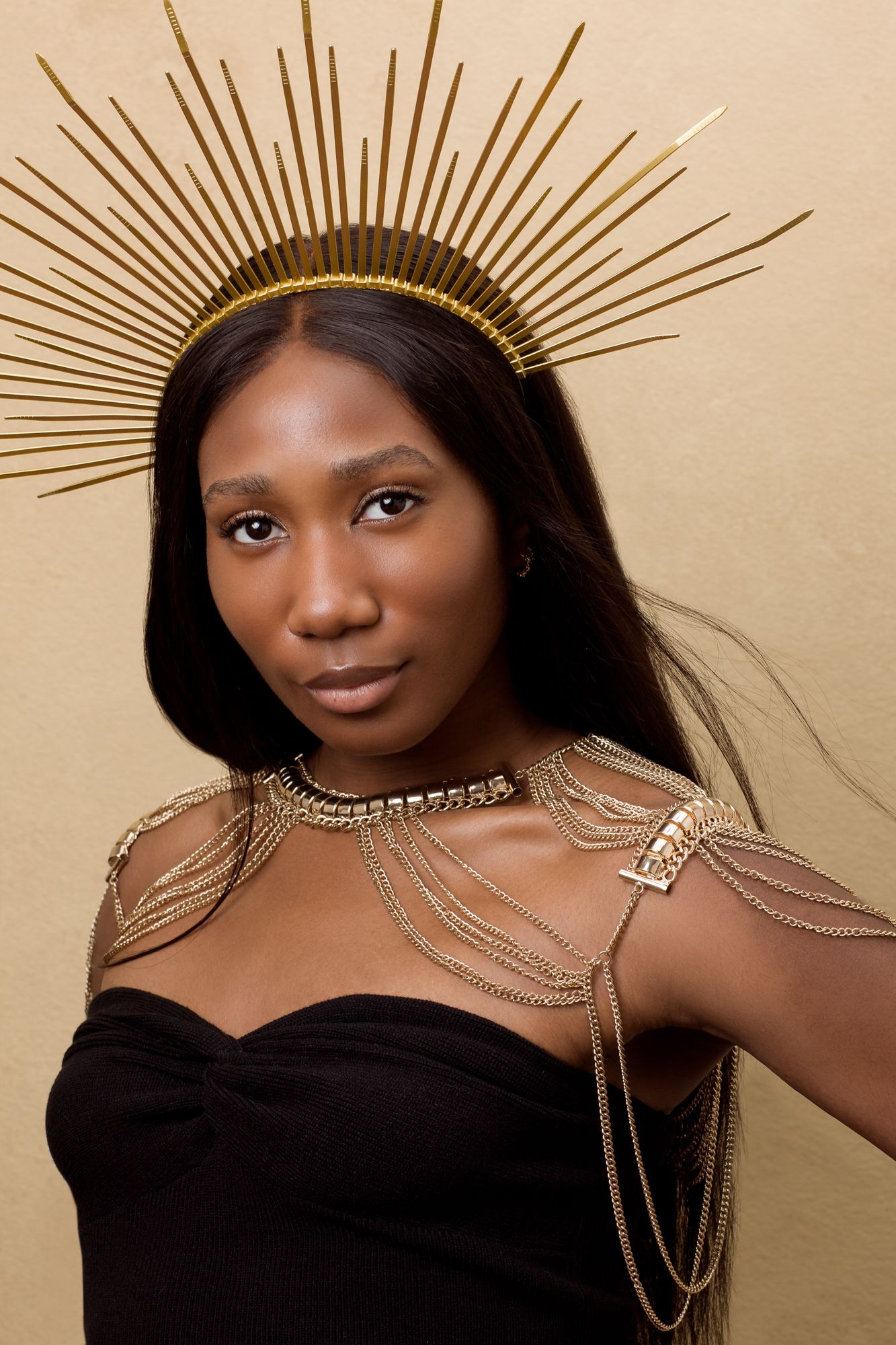 Artistic portrait series featuring gold sunburst crown and draped chain accessories against neutral backdrop.