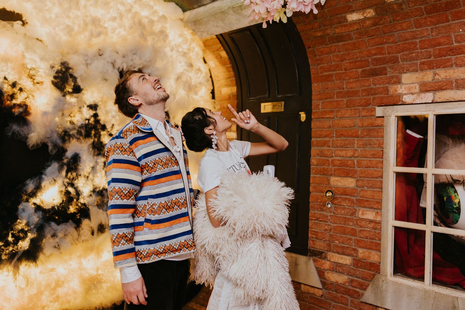 A couple dancing and twirling together in front of a brick wall with holiday decorations.