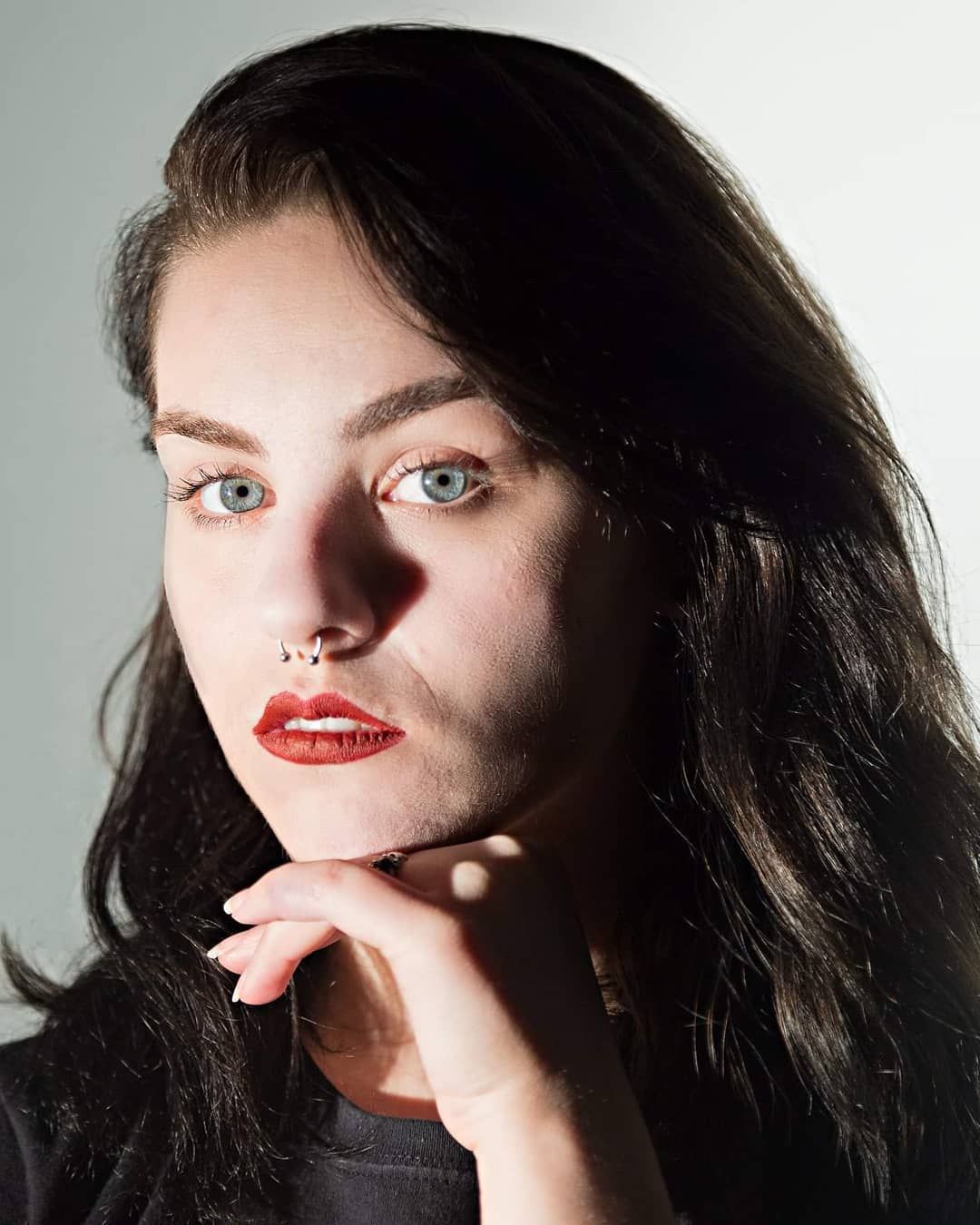 A dramatic portrait series showing different angles and poses in moody lighting with dark hair and bold red lipstick.