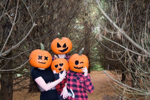 Family poses with pumpkin decorations in a rustic outdoor setting during autumn.