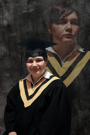 Graduate in black cap and gown with gold trim poses against a dark textured background.