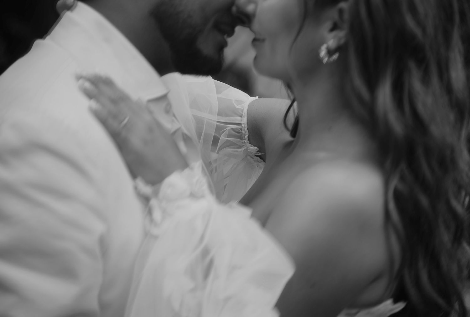 A romantic black and white close-up moment between a couple sharing an intimate kiss.