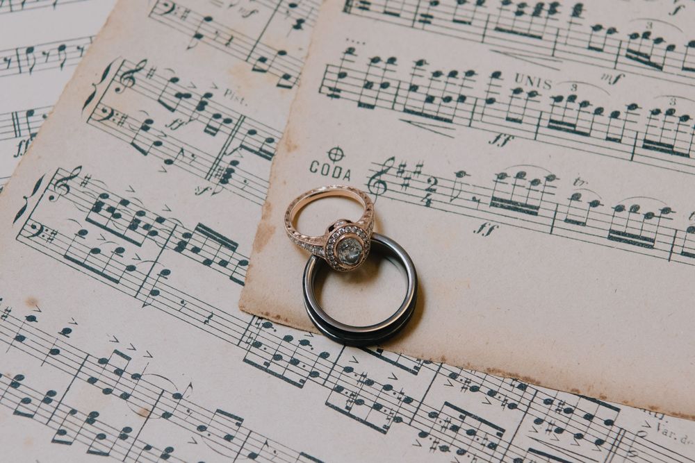 Diamond engagement ring and wedding band resting on vintage sheet music, perfect for romantic wedding photography.