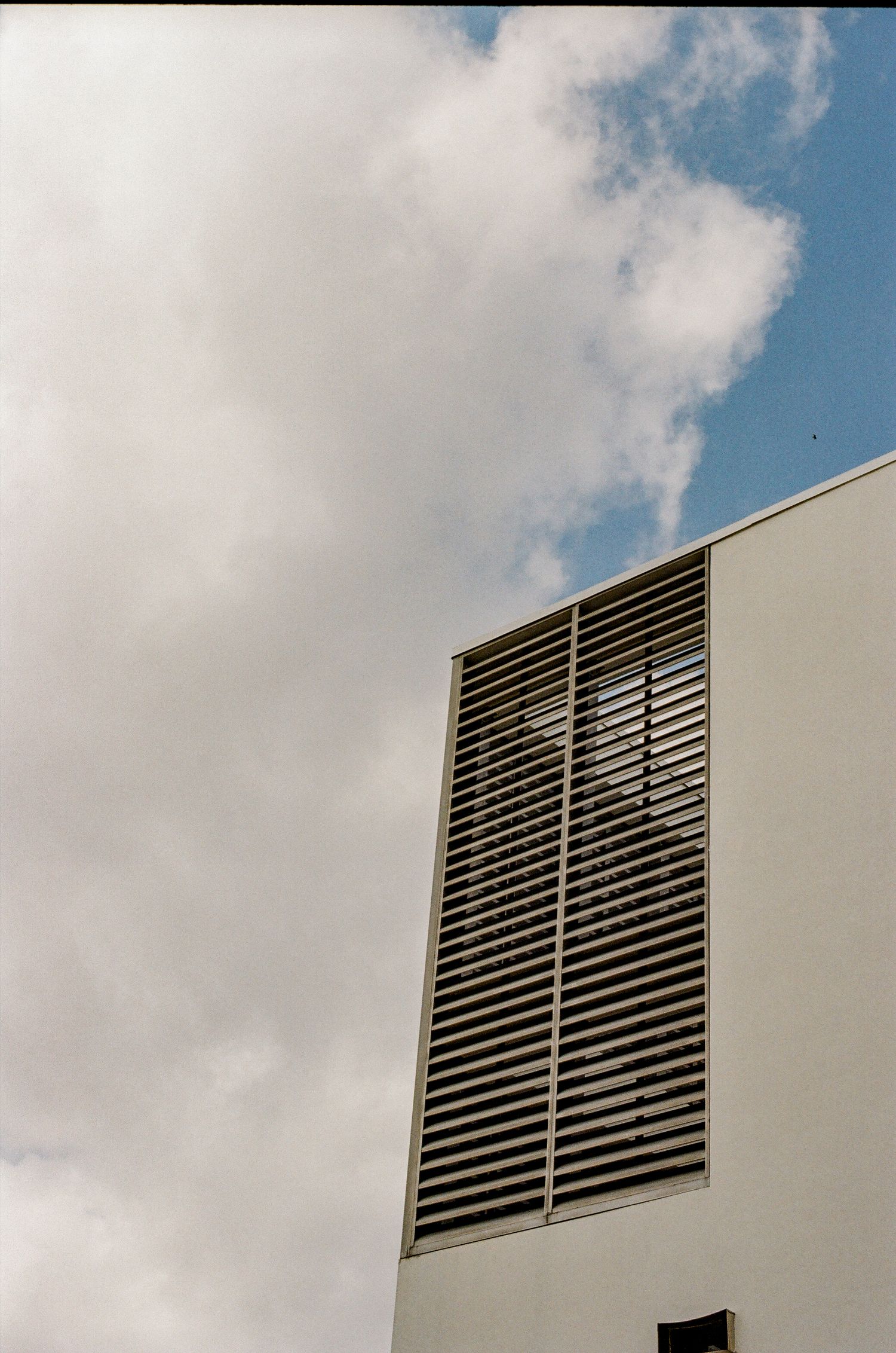Modern architectural detail showing white geometric building elements against a cloudy blue sky with dramatic angles.