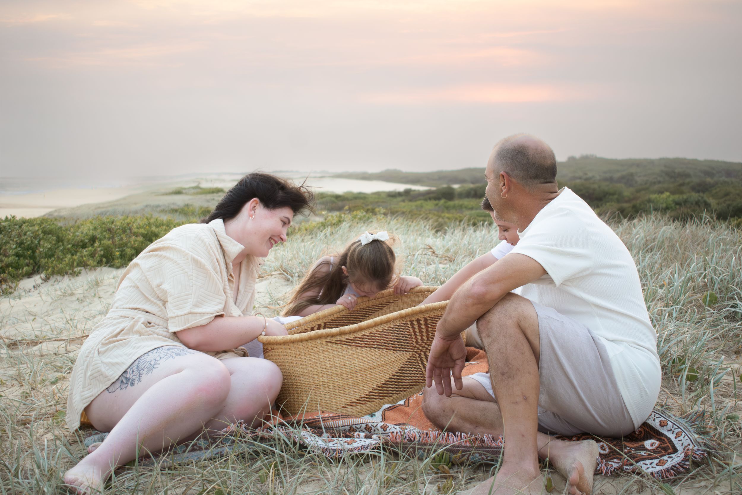 Newcastle newborn baby photographer capturing baby in bassinet surrounded by mother, father, siblings